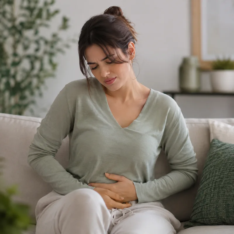 Mulher com desconforto abdominal no sofá